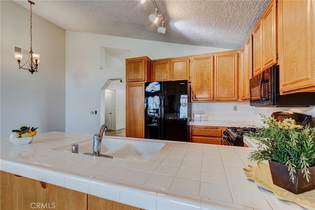 kitchen featuring tile counters, black appliances, kitchen peninsula, and vaulted ceiling