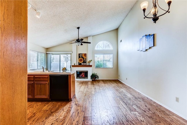 kitchen with lofted ceiling, fridge, a textured ceiling, a brick fireplace, and light wood-type flooring