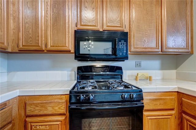 kitchen with tile counters and black appliances