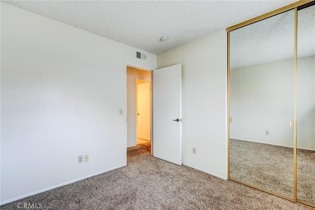 unfurnished bedroom featuring carpet, a textured ceiling, and a closet