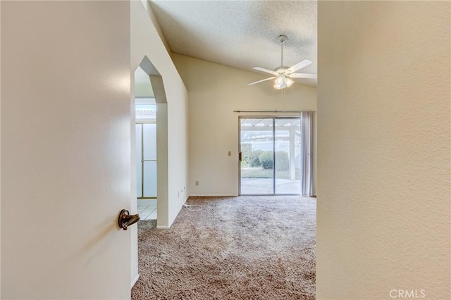 spare room featuring a textured ceiling, vaulted ceiling, ceiling fan, and carpet