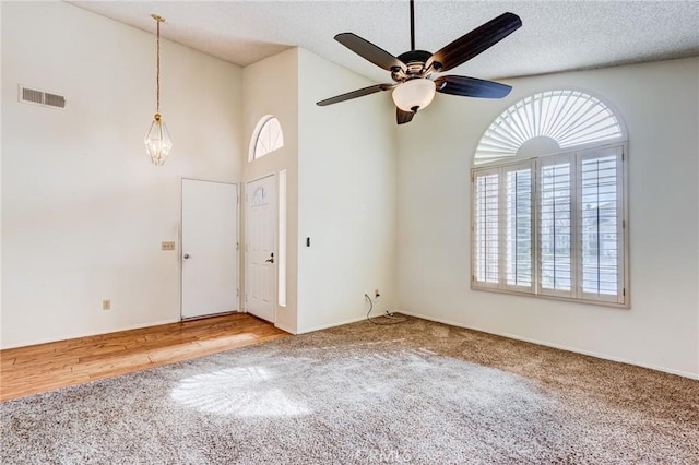 spare room with ceiling fan, carpet floors, a textured ceiling, and a high ceiling