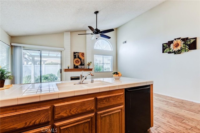 kitchen featuring plenty of natural light, tile counters, sink, and a textured ceiling