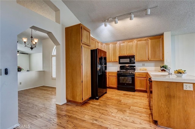 kitchen with hanging light fixtures, sink, a textured ceiling, and black appliances