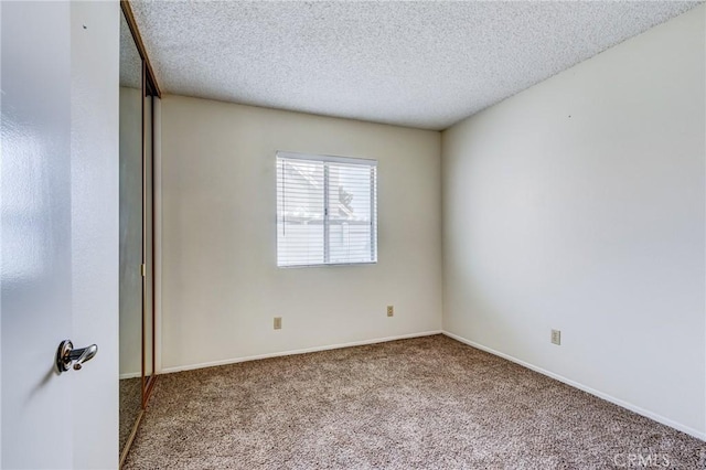 spare room featuring light carpet and a textured ceiling