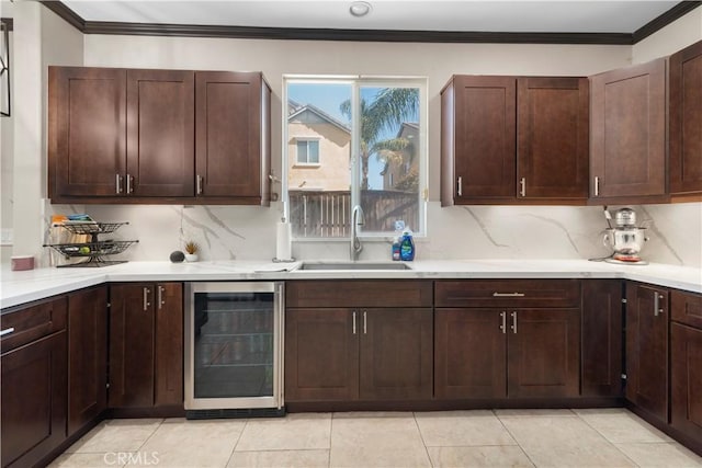 kitchen with sink, beverage cooler, decorative backsplash, crown molding, and dark brown cabinets