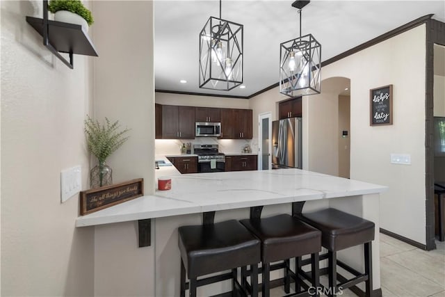 kitchen with stainless steel appliances, dark brown cabinetry, ornamental molding, a kitchen bar, and kitchen peninsula