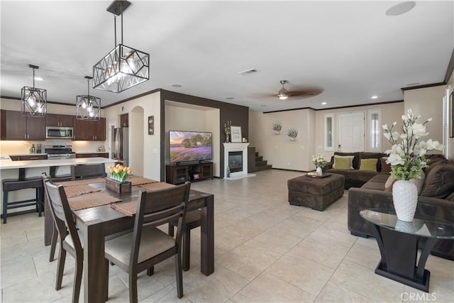 tiled dining area featuring crown molding and ceiling fan