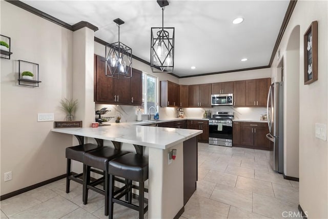 kitchen with decorative light fixtures, ornamental molding, stainless steel appliances, and a kitchen breakfast bar