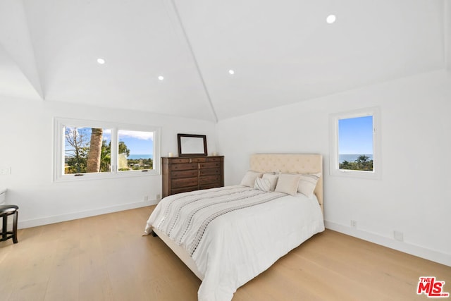 bedroom with vaulted ceiling, multiple windows, and light wood-type flooring