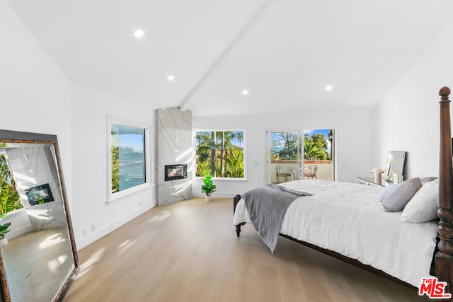 bedroom with beamed ceiling, a high end fireplace, access to exterior, and light hardwood / wood-style floors