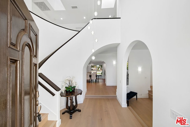 foyer featuring a towering ceiling and light wood-type flooring