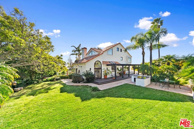 rear view of house with a patio and a lawn