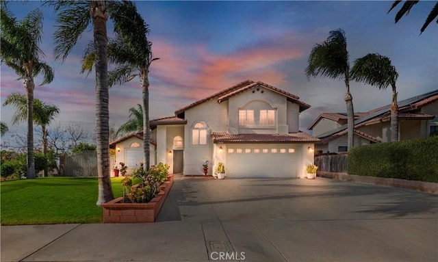 mediterranean / spanish-style house featuring a garage and a lawn