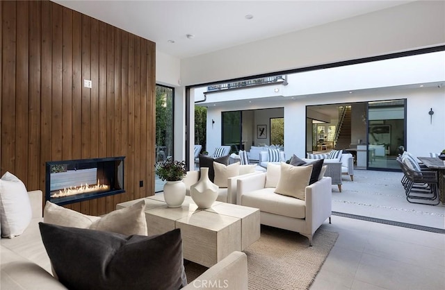 living room featuring a large fireplace and wood walls