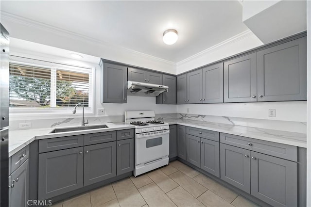 kitchen with white range with gas cooktop, sink, light stone counters, and gray cabinetry