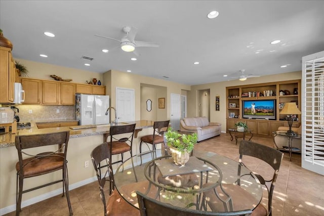 tiled dining room with sink, built in features, and ceiling fan