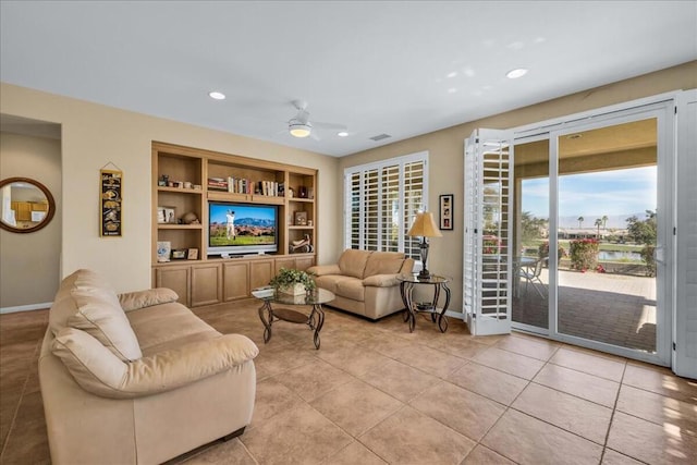 living room featuring built in shelves, ceiling fan, and light tile patterned floors