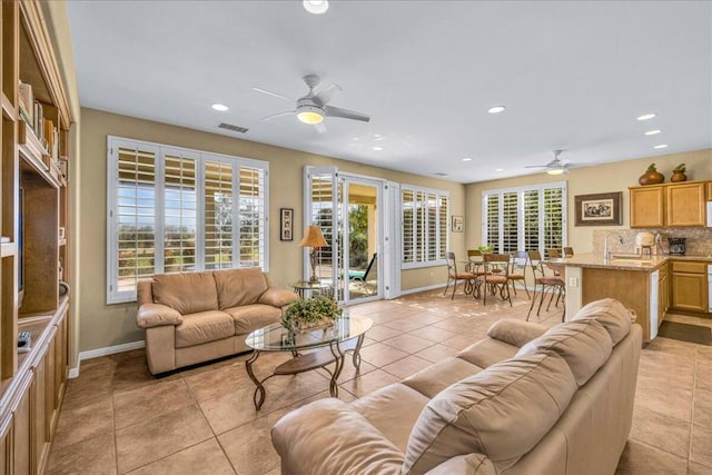 tiled living room with ceiling fan, a healthy amount of sunlight, and sink