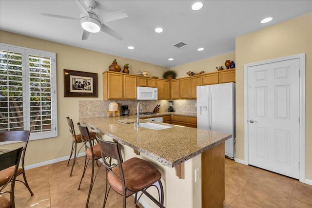 kitchen with a kitchen breakfast bar, decorative backsplash, light stone counters, kitchen peninsula, and white appliances