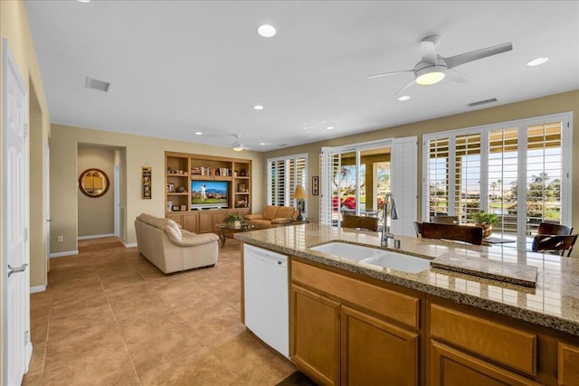 kitchen featuring sink, light tile patterned floors, white dishwasher, ceiling fan, and light stone countertops