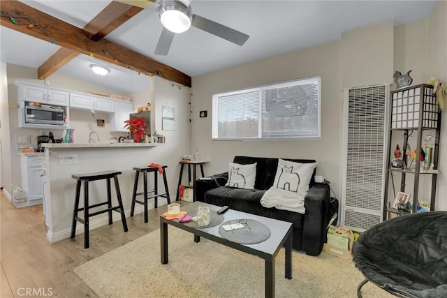 living room featuring lofted ceiling with beams, light hardwood / wood-style floors, and ceiling fan