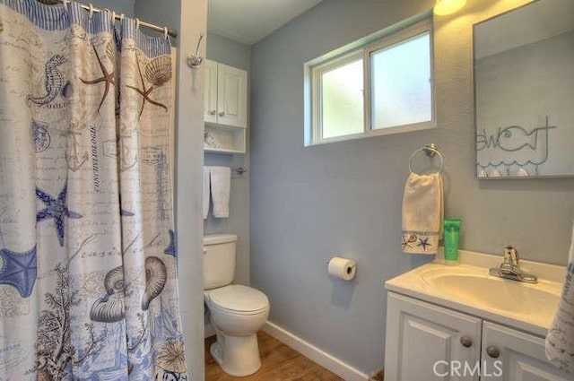 bathroom featuring hardwood / wood-style flooring, vanity, walk in shower, and toilet