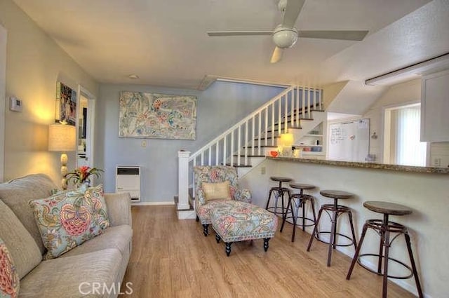 living room featuring ceiling fan, heating unit, and light wood-type flooring