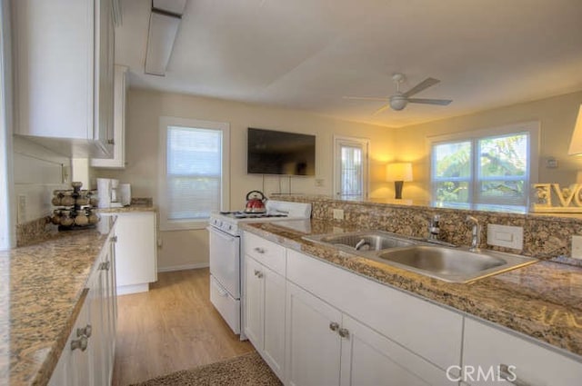 kitchen featuring sink, white cabinetry, light stone countertops, white range with gas cooktop, and light wood-type flooring