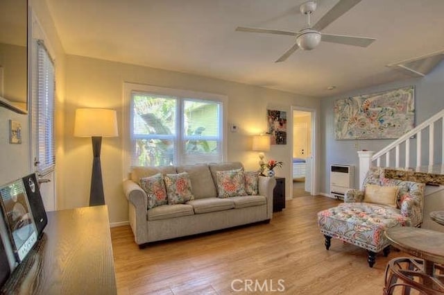 living room featuring ceiling fan, heating unit, and light wood-type flooring