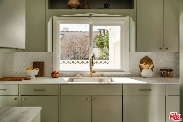 kitchen featuring tasteful backsplash, sink, light stone counters, and green cabinetry