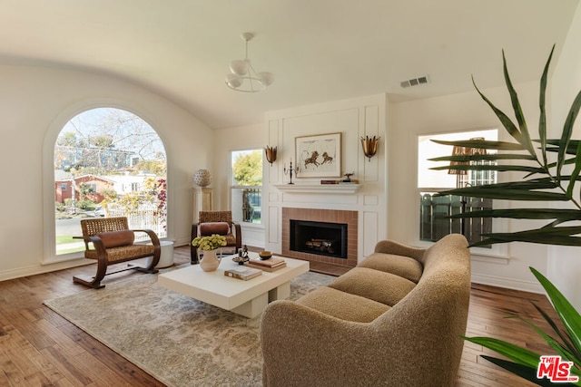 living room with lofted ceiling, a fireplace, and light hardwood / wood-style flooring