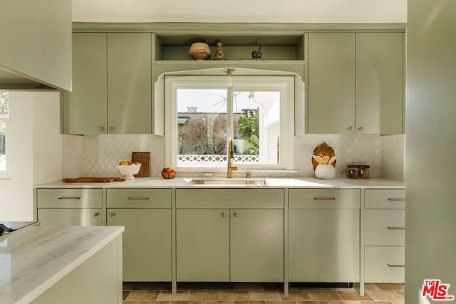 kitchen with tasteful backsplash, sink, black electric cooktop, and green cabinetry