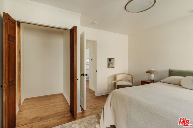 bedroom featuring crown molding and light wood-type flooring