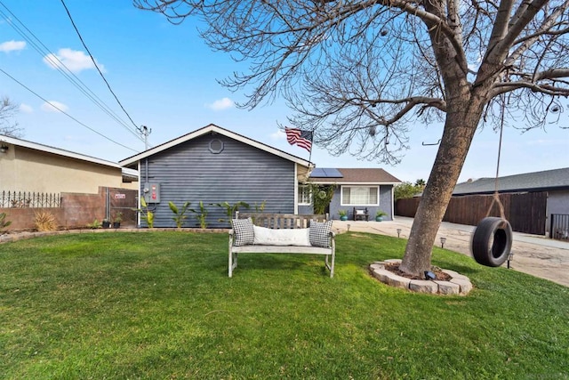 rear view of house with a yard and solar panels