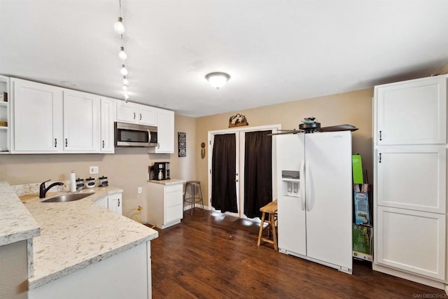 kitchen with sink, white cabinetry, dark hardwood / wood-style floors, light stone counters, and white fridge with ice dispenser