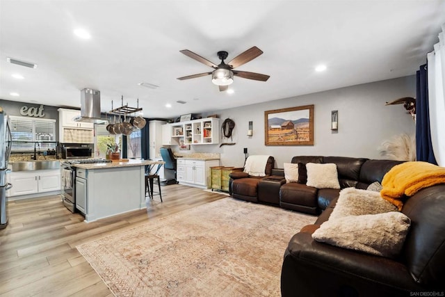 living room featuring sink, ceiling fan, and light wood-type flooring