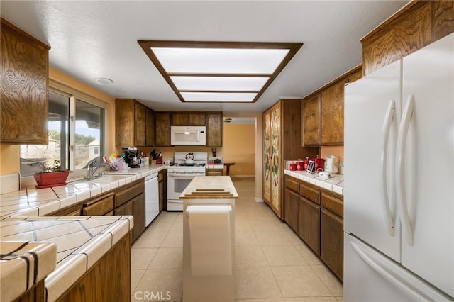 kitchen with sink, white appliances, tile countertops, and light tile patterned flooring