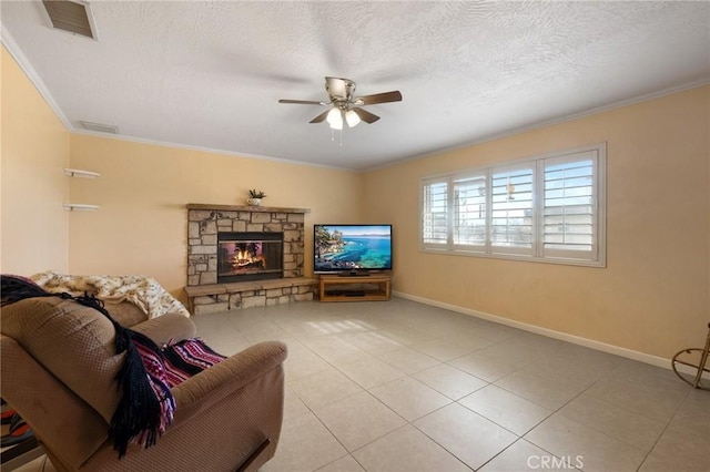 living room featuring light tile patterned floors, ceiling fan, a fireplace, ornamental molding, and a textured ceiling