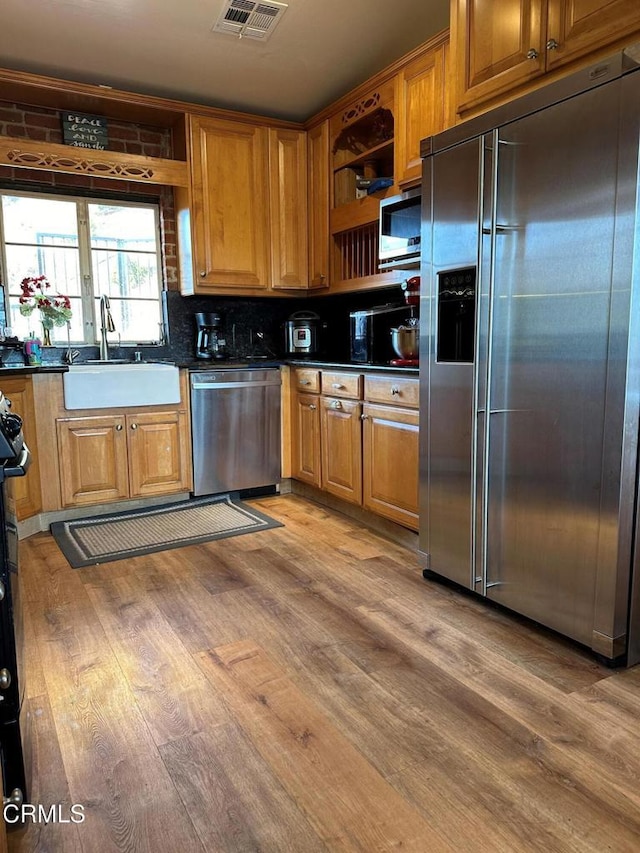 kitchen featuring decorative backsplash, appliances with stainless steel finishes, sink, and wood-type flooring