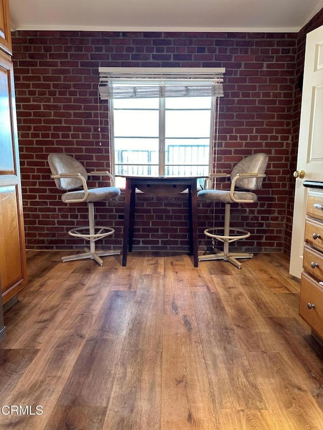 sitting room with hardwood / wood-style flooring and brick wall