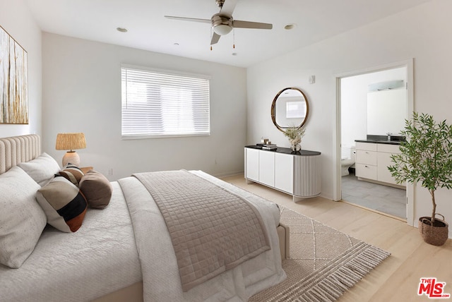 bedroom featuring ensuite bathroom, sink, ceiling fan, and light wood-type flooring