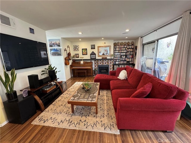 living room featuring a tiled fireplace and hardwood / wood-style floors