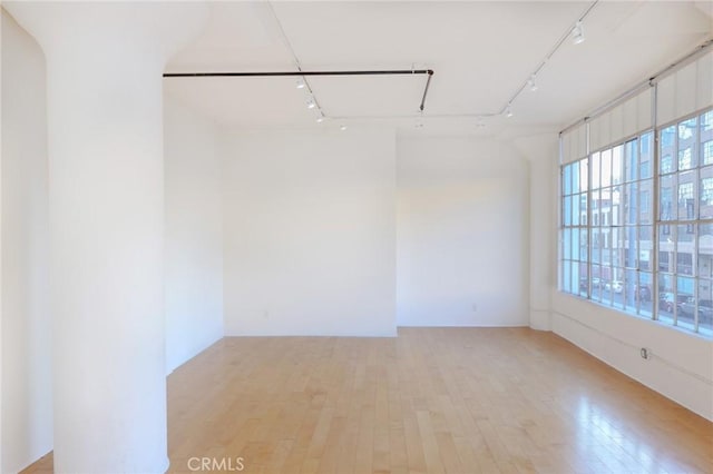 empty room featuring track lighting and light wood-type flooring