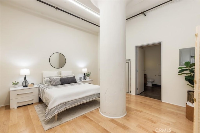 bedroom with a towering ceiling, light hardwood / wood-style floors, and ensuite bathroom