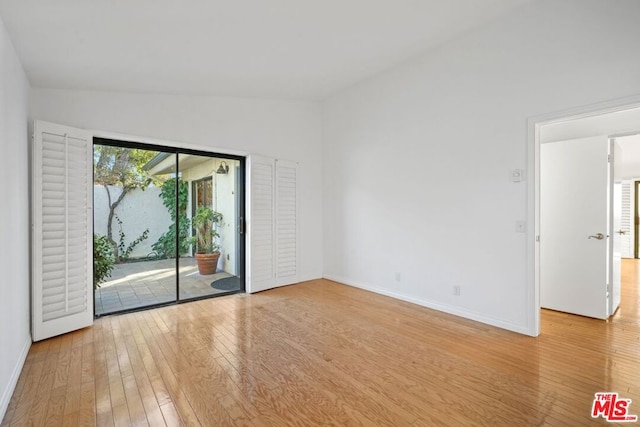 empty room with lofted ceiling and light hardwood / wood-style floors