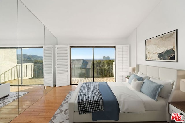 bedroom featuring multiple windows, access to outside, and light hardwood / wood-style floors