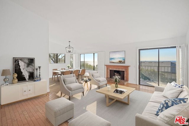 living room featuring a tiled fireplace, an inviting chandelier, and light hardwood / wood-style floors