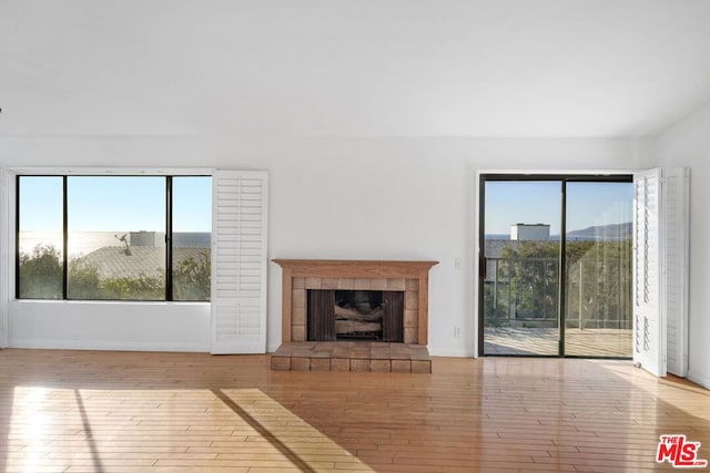 unfurnished living room with a tile fireplace, a mountain view, and light hardwood / wood-style floors