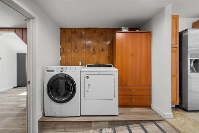 laundry room with washer and clothes dryer and light hardwood / wood-style floors